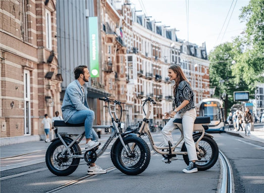 Man and woman riding Grandeux X-Series electric bikes, featuring the Xcite step-thru and Xplore over-frame models, designed for city commuting and urban adventures